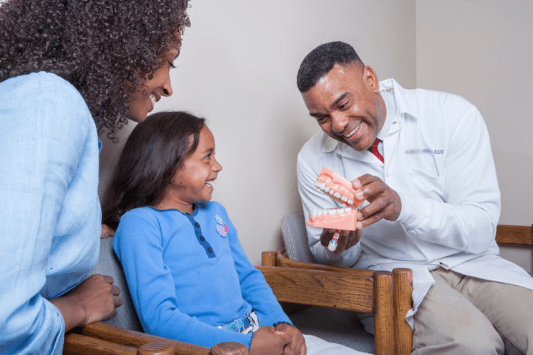 ICON locum tenens dentists. Dentist holds teeth model for child patient.