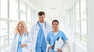 three advanced practice providers walking down a sunlit hallway in a hospital